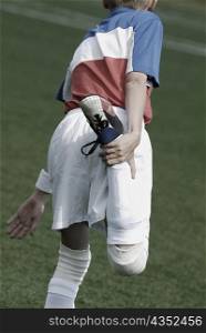 Rear view of a soccer player stretching his leg
