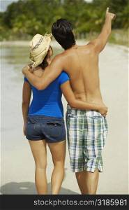 Rear view of a teenage girl with her arm around a young man