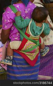 Rear view of a woman carrying her baby on her back, Luang Prabang, Laos