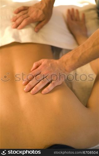 Rear view of a woman getting a back massage from a massage therapist
