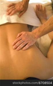Rear view of a woman getting a back massage from a massage therapist