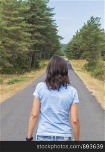 Rear view of a woman in jeans walking on road
