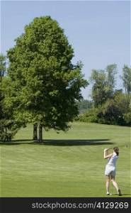 Rear view of a woman playing golf on a golf course