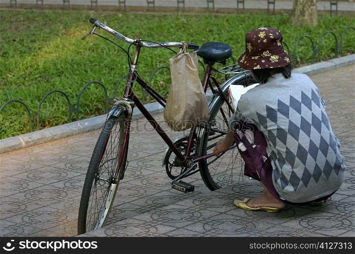 Rear view of a woman repairing a bicycle, Hanoi, Vietnam