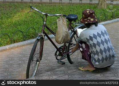 Rear view of a woman repairing a bicycle, Hanoi, Vietnam