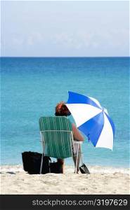Rear view of a woman sitting on the beach, South Beach, Miami, Florida, USA