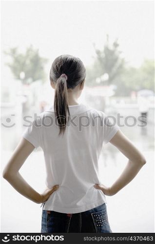 Rear view of a woman standing with her arms akimbo
