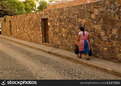 Rear view of a woman walking on a footpath, Mexico