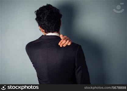 Rear view of a young businessman massaging his sore neck