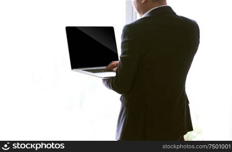Rear view of a young businessman working of a laptop , blank screen for pupose design use .