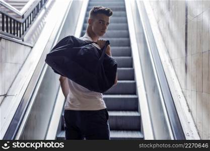 Rear view of a young caucasian male moving up on an escalator at the airport.