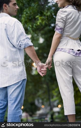 Rear view of a young couple holding hands of each other