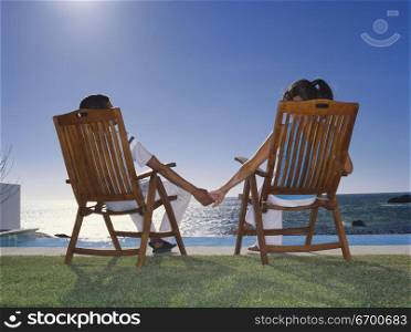 Rear view of a young couple sitting on a chair holding hands