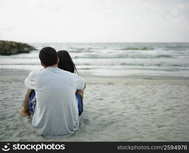 Rear view of a young couple sitting on the beach