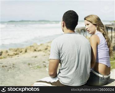 Rear view of a young couple sitting on the beach