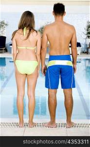 Rear view of a young couple standing at the poolside