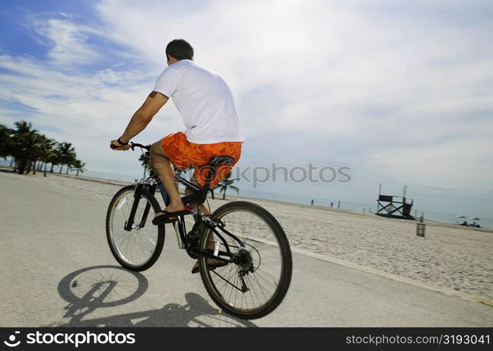 Rear view of a young man cycling