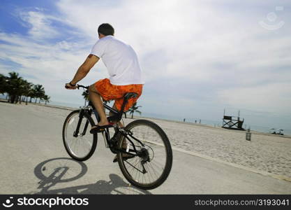 Rear view of a young man cycling