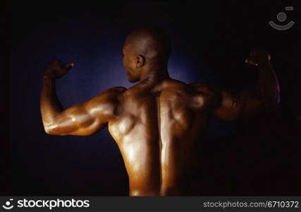 Rear view of a young man flexing his biceps