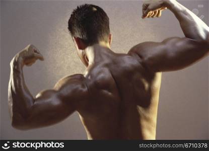 Rear view of a young man flexing his biceps