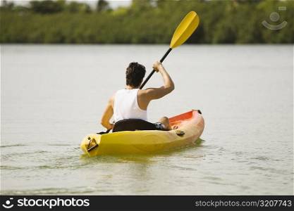 Rear view of a young man kayaking in a lake