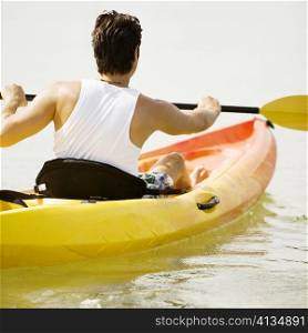 Rear view of a young man kayaking in a lake