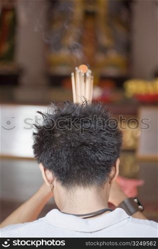 Rear view of a young man praying in a temple