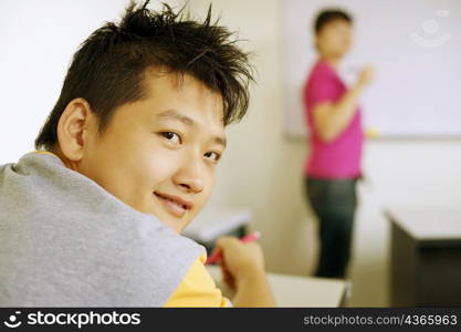 Rear view of a young man sitting in a classroom and smiling