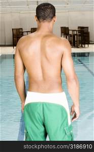 Rear view of a young man standing at the poolside