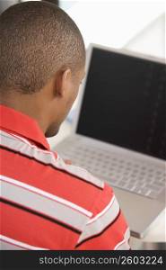 Rear view of a young man using a laptop
