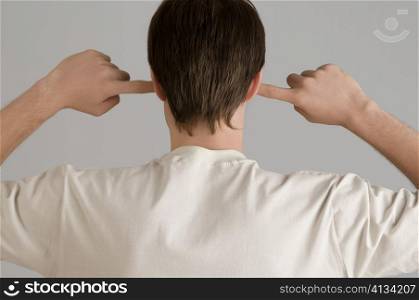 Rear view of a young man with his fingers in his ears