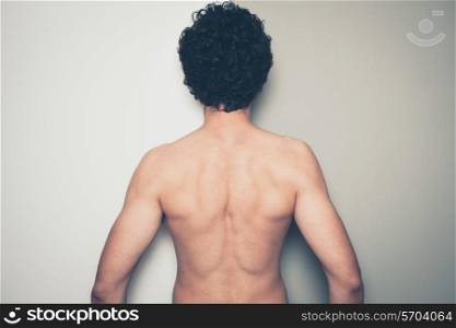 Rear view of a young shirtless man against a green and white background