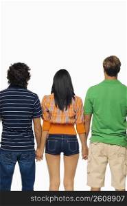 Rear view of a young woman and two men standing with holding their hands