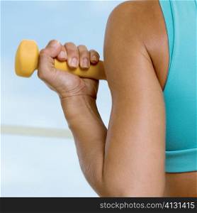 Rear view of a young woman exercising with a dumbbell