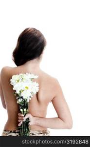 Rear view of a young woman hiding a bunch of flowers behind her back