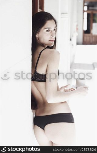 Rear view of a young woman in lingerie holding a cup of tea
