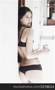 Rear view of a young woman in lingerie holding a cup of tea
