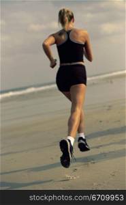 Rear view of a young woman running on the beach