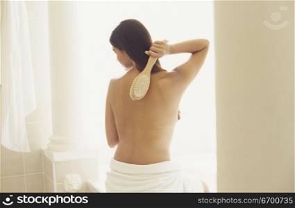 Rear view of a young woman scrubbing her back
