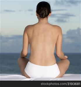 Rear view of a young woman sitting in a lotus position