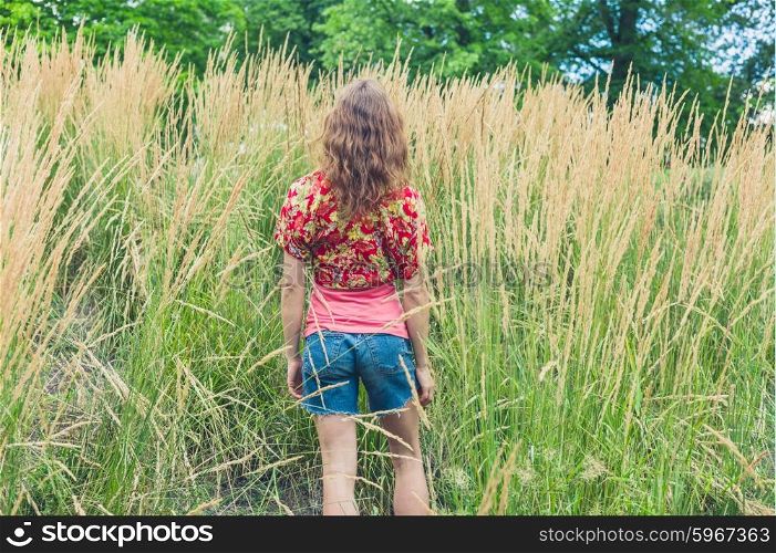 Rear view of a young woman standing in some tall grass