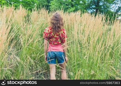 Rear view of a young woman standing in some tall grass
