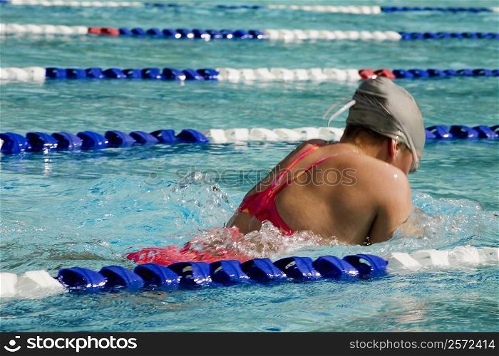 Rear view of a young woman swimming in a swimming pool