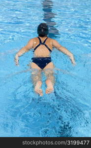 Rear view of a young woman swimming in a swimming pool