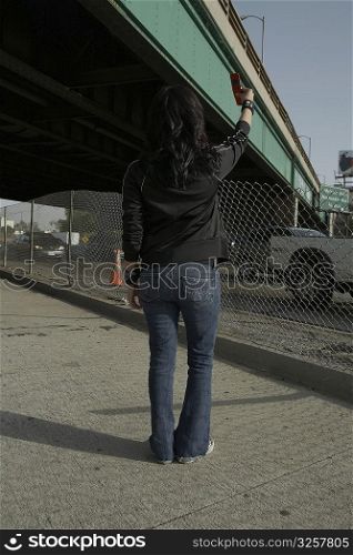 Rear view of a young woman taking a photograph of herself with a mobile phone