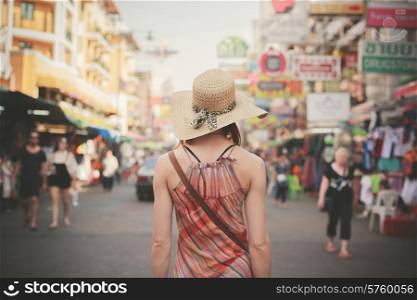 Rear view of a young woman walking the famous backpacker street Khao San in Bangkok, Thailand