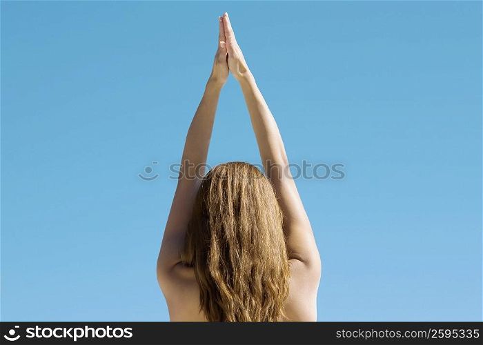 Rear view of a young woman with her arms raised