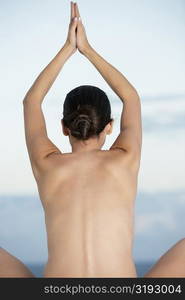 Rear view of a young woman with her arms raised