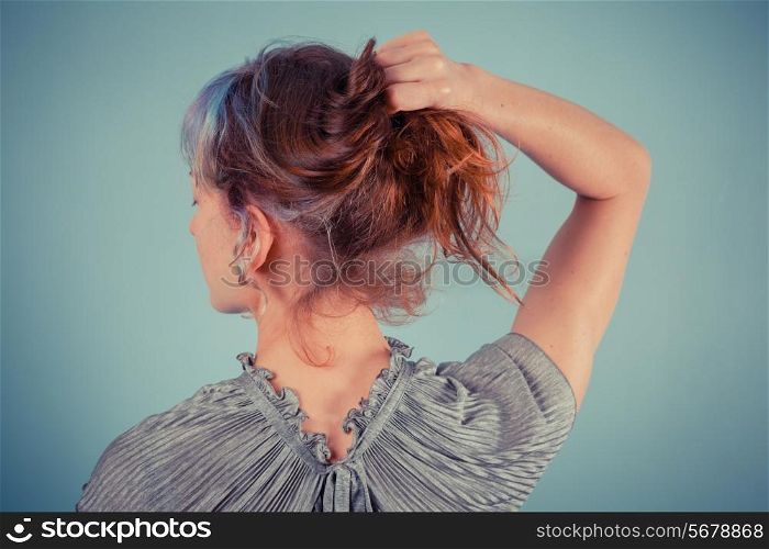 Rear view of an elegant young woman adjusting her hair