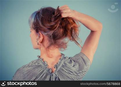 Rear view of an elegant young woman adjusting her hair